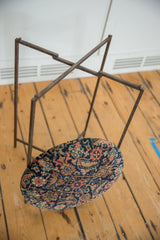 Reclaimed rug fragment side table with its cushioned top separated from the metal base.