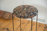 Angled view of the side table's cushioned top, showing the antique Persian rug's navy and saffron floral pattern.