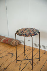 Profile of the reclaimed side table highlighting its antique Persian rug top and slim metal frame.