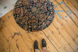 Overhead view of the antique rug fragment side table showing its round shape, intricate pattern, and scale.