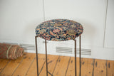 Angled profile of a reclaimed side table with a round, antique Persian Fereghan rug top.