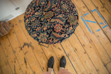 Reclaimed side table with a cushioned antique Persian rug top, seen from an overhead angle.