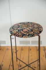 Angled view of the reclaimed side table with its patterned antique rug top on a thin metal frame.