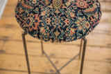 Detailed geometric pattern in navy, ivory, and saffron on the cushioned antique rug table top.