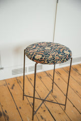 Angled view of the reclaimed side table with a patterned antique rug top and slim metal legs.