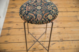 Overhead view of the round side table's antique Fereghan rug top and slender metal base.