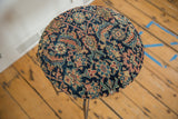 Overhead view of the side table's antique rug top with a dense navy and saffron pattern.