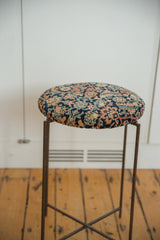 Profile view of the reclaimed side table showing its antique rug top and vintage metal base.