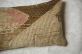 Vintage Oushak rug fragment pillow's textured pile in distressed beige, brown, and muted pink.