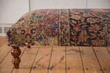 Storied wear and a visible patch on an antique Persian Kerman rug ottoman's upholstery.