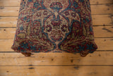 Top view of the antique Kerman rug ottoman showing its intricate floral pattern and textured, time-worn surface.