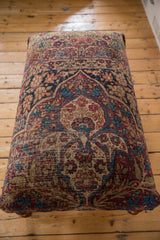 High perspective view of the Kerman rug ottoman's full-length pattern and aged patina.