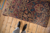 Full length of the antique Kerman rug ottoman seen from above, showing its rich, time-worn floral pattern.
