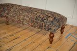 Detailed textile and curved wooden leg on an antique Kerman Persian rug ottoman.