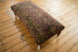 Elevated view of the antique Persian Kerman rug ottoman, showing its full rectangular shape.