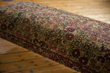 Storied wear and low pile texture of the antique Persian Kerman rug ottoman's surface.