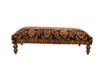 Vintage Persian rug ottoman with floral terracotta and jade green patterns on dark turned wood legs.
