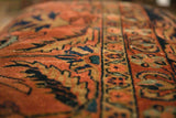 Close detail of the vintage rug ottoman's hand-knotted pile in dusty rose, navy blue, and gold.