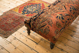 Side profile of the vintage Lilihan rug ottoman featuring dusty rose and navy blue floral patterns.