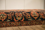 Detailed pattern of the vintage Lilihan rug's navy blue border on the custom ottoman.