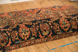 Detailed view of the vintage rug ottoman's navy blue border with terracotta and jade floral patterns.