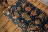 Close-up: antique Ziegler Mahal fragment, dark navy, terracotta, moss green blossoms, vines, evident wear.