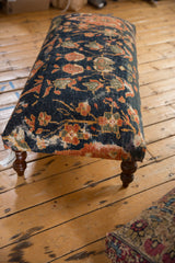 Rustic wooden floorboards and corner of a colorful floral patterned textile.