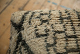 The plush, woolly texture of the vintage Moroccan rug ottoman's ivory and gray upholstery.