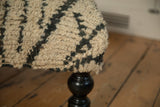 Close-up of the vintage Moroccan rug's shaggy wool texture and abstract design on the ottoman's corner.