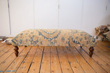 Full-length profile of the vintage Persian rug ottoman on its turned wooden legs.