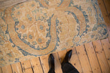 Overhead view of the vintage Persian rug ottoman's worn texture and floral pattern.