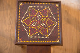 End table corner showing wear on dark brown frame with dot painted border.