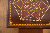 Painted vintage end table corner, showing red, yellow, and cream dot pattern with edge wear.