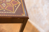 Painted vintage end table corner, with geometric dot pattern and signs of age.