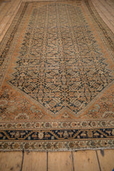 Angled view of a vintage Malayer runner showing its distressed copper and indigo Herati pattern.