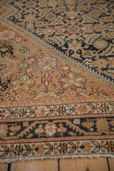 Low angle on a distressed Malayer rug showing the vine border and low-pile Herati field.