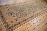 Angled full view of a distressed Malayer runner featuring a copper and deep indigo Herati pattern.