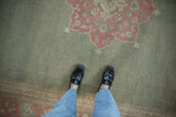 Faded sage green field with soft pink medallion and patterned border of a vintage distressed Agra rug.
