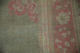 Distressed Armenian Agra rug corner, faded pink floral vinery on dusty sage low pile.