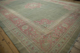 Vintage distressed Armenian Agra carpet corner with fading pink floral vinery border on a soft green field.