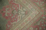 Distressed Armenian Agra carpet corner with faded pink floral vinery and low pile.