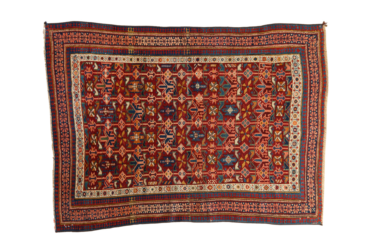 Antique hand-knotted Caucasian Seichour rug, rich red field with multicolor geometric pinwheel motifs.