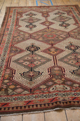 Vintage Malayer rug's lower section with coral border, camel shield motifs, and seeded field.