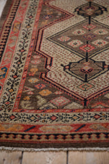 Vintage Malayer rug with geometric border, diamond medallions, seeded field, camel, red, navy tones.
