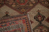 Folded vintage Malayer rug showing camel, ivory, red diamond field motifs and side selvage.