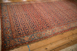 Perspective view of the vintage Malayer carpet's allover red Herati pattern on a navy blue ground.