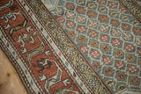 Distressed Kurd rug detail: madder root border, geometric vine motif, dusty blue-green field.