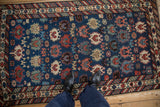 Overhead perspective of an antique Caucasian rug featuring serrated floral motifs on a sapphire blue ground.
