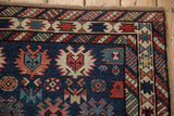 Corner of an antique Caucasian rug showing its geometric serrated palmette and checkered borders.