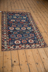 Angled perspective of an antique Caucasian rug showing its unidirectional pattern and complex geometric borders.